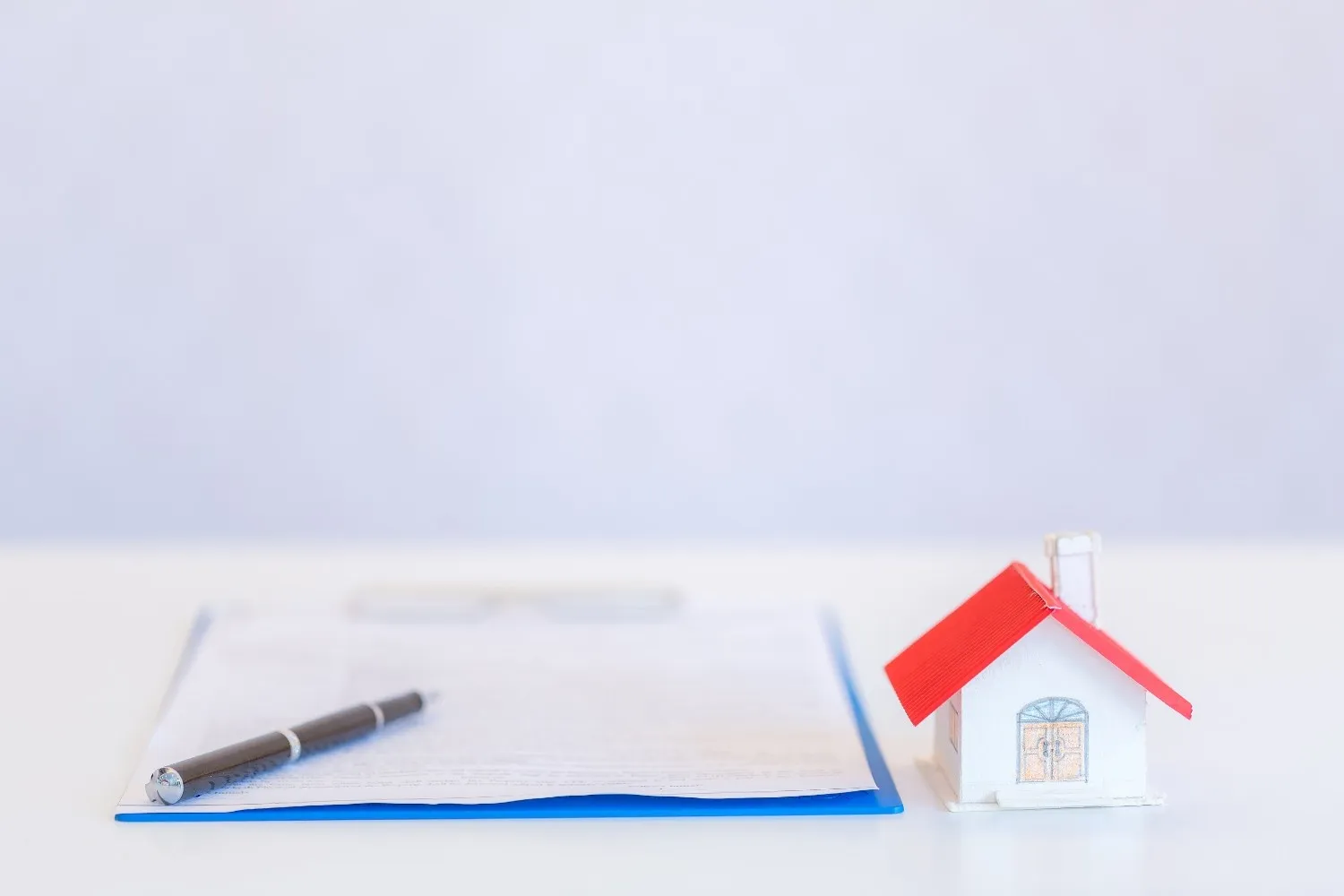 Model house on a desk next to a signed home insurance document